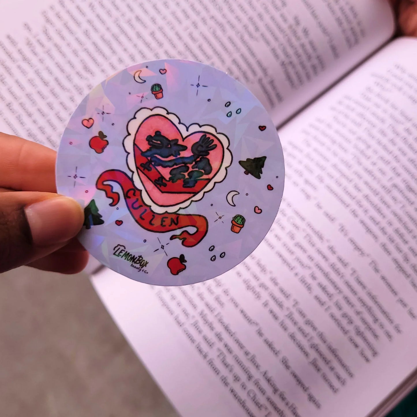 Circular sticker with heart design held over an open book