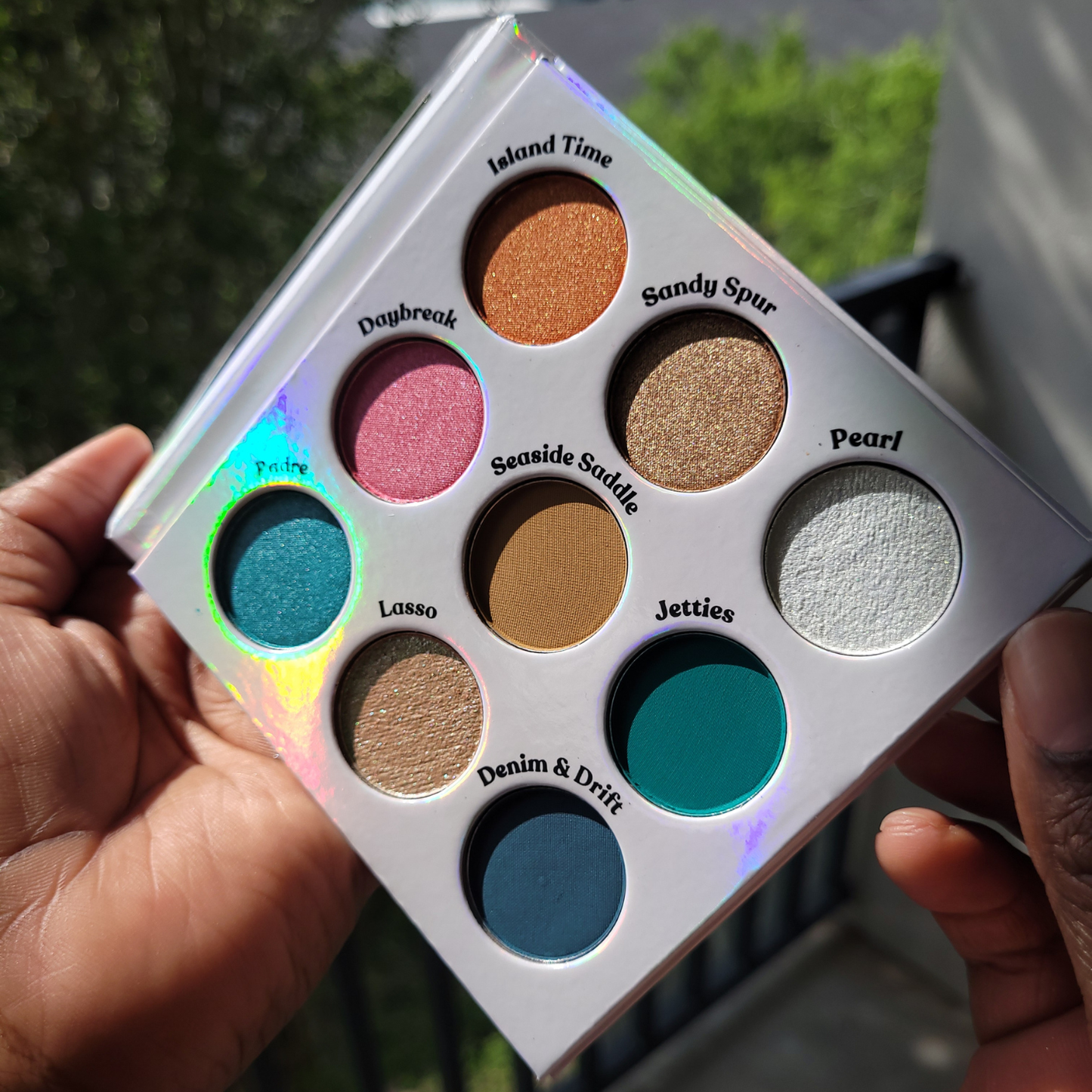 Makeup palette with various colors held by a hand, Seaside Lasso Eyeshadow palette