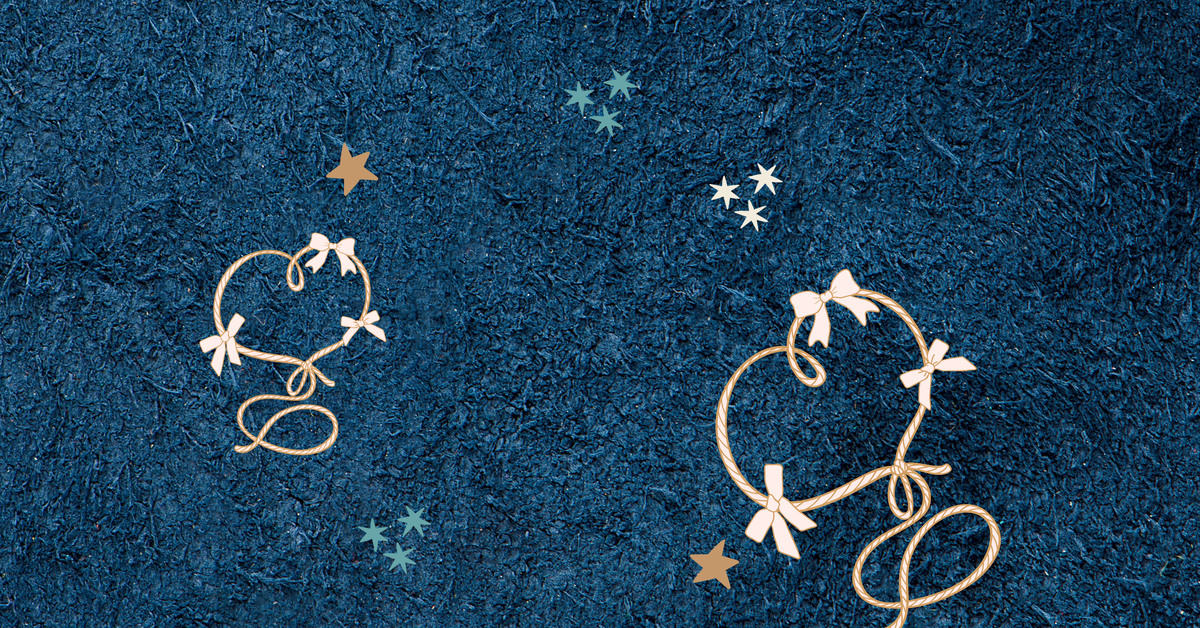 A textured dark blue fabric backdrop decorated with embroidered cream and gold heart-and-bow motifs and small star accents.