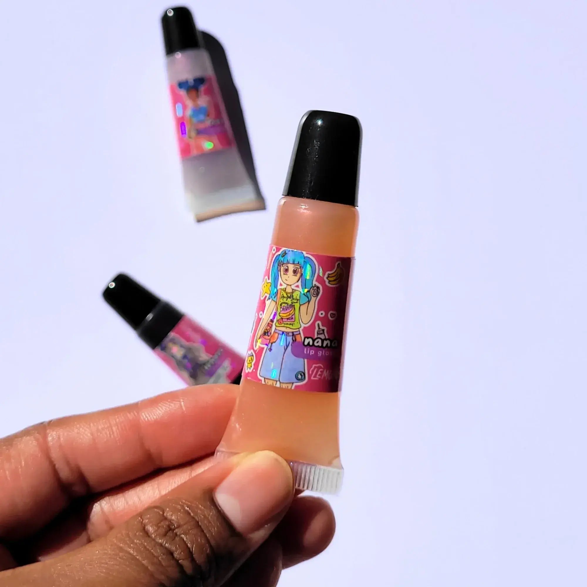 Lemon Box Beauty Nana Anime Shine Lip Gloss - shimmering peachy-pink vegan lip oil in a squeeze tube with custom Heisei retro anime character artwork.
