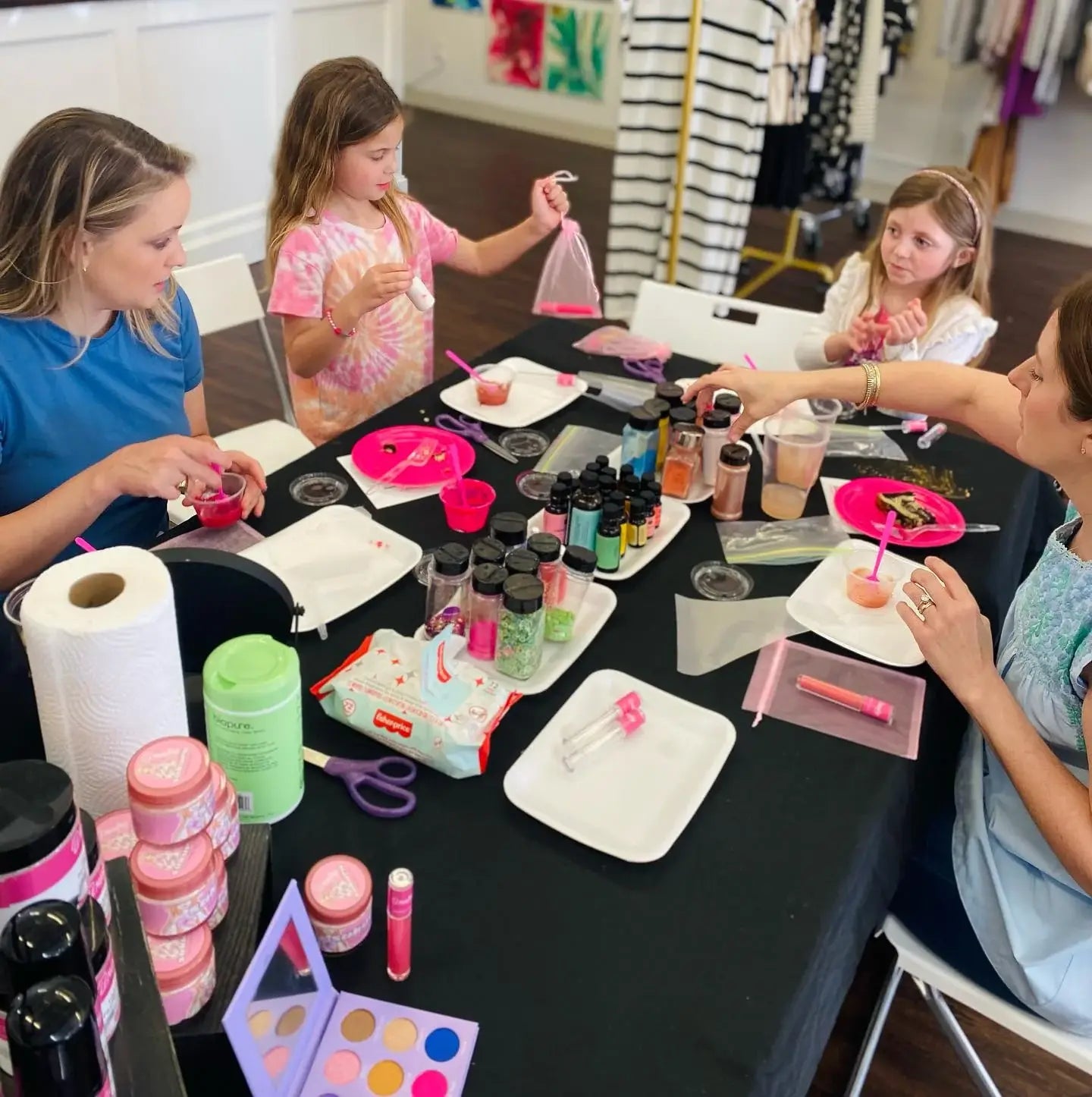 Children and adults engaged in a craft activity at a table with various supplies.