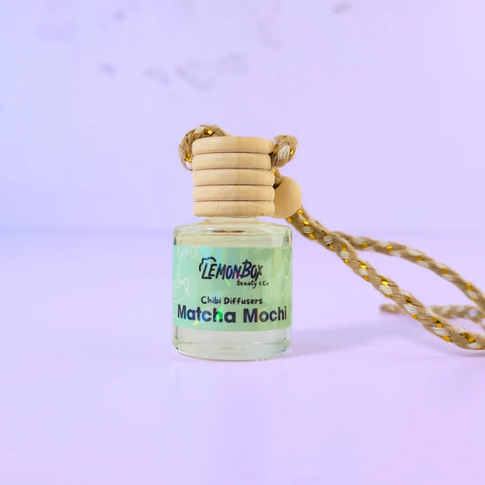 Lemon Box Beauty Matcha Mochi Chibi Diffuser - hanging car air freshener glass bottle with wooden cap and braided rope on a lavender background.