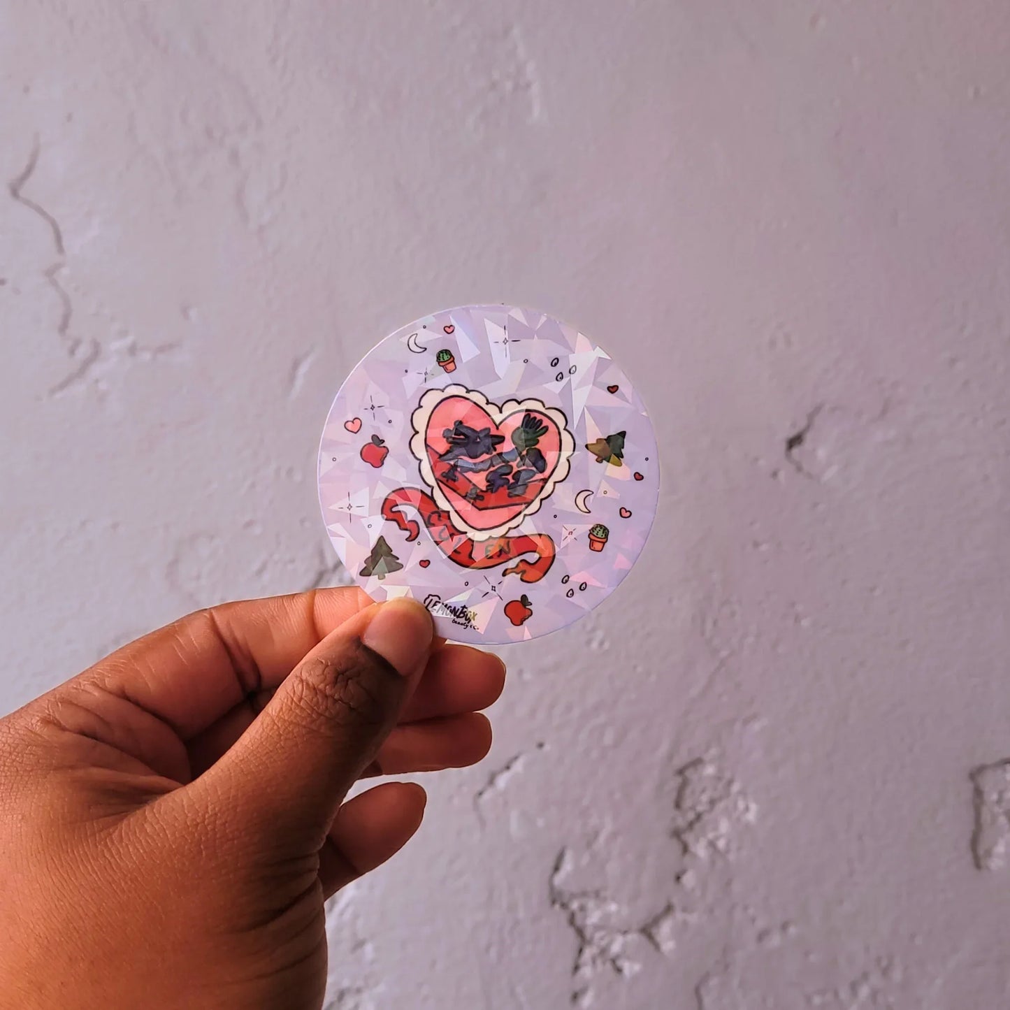 Hand holding a circular sticker of Cullen Crest against a plain background
