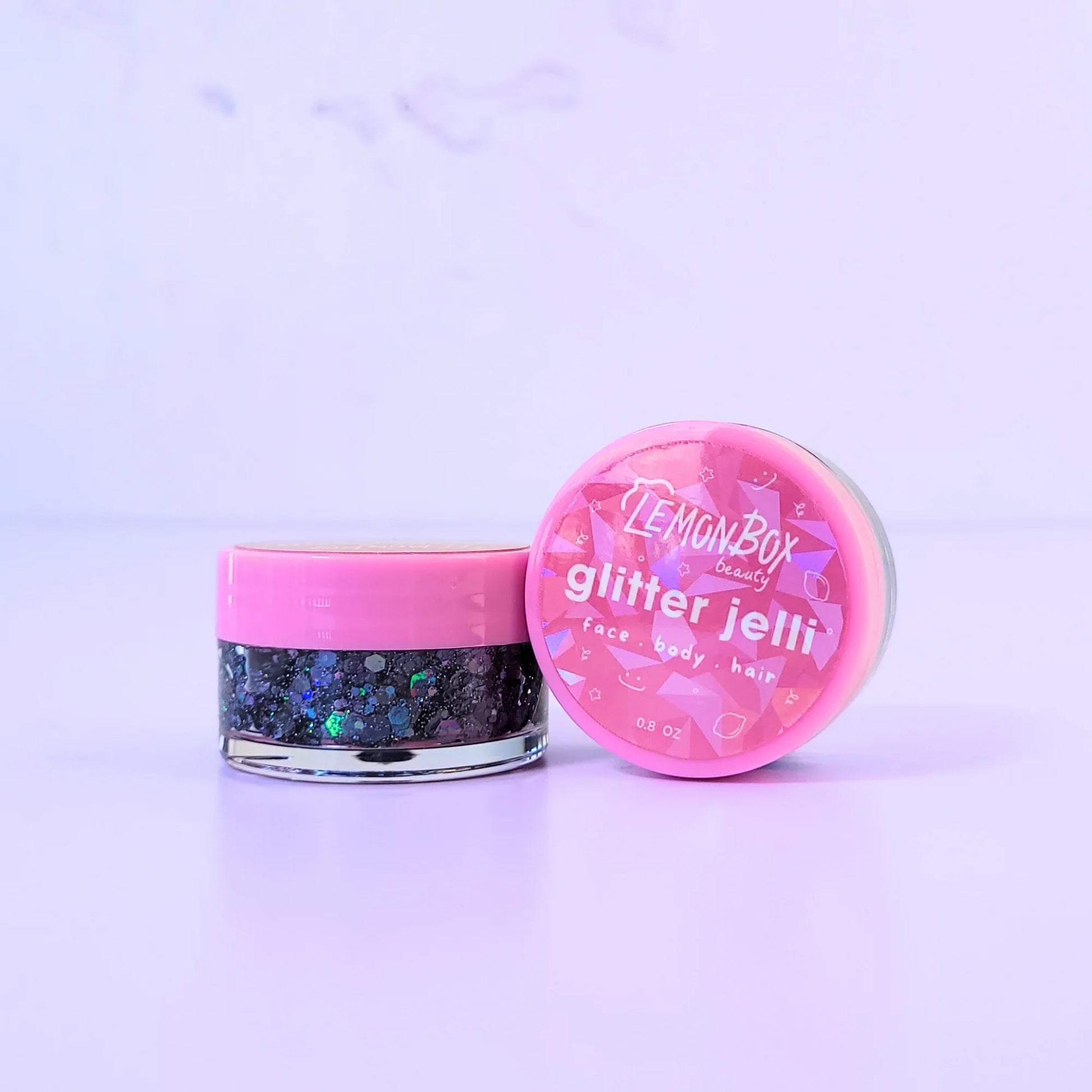 Lemon Box Beauty Disco Dream Glitter Jelli - holographic black and multi-colored chunky body glitter in a clear jar with a texture swatch on a pink spatula.