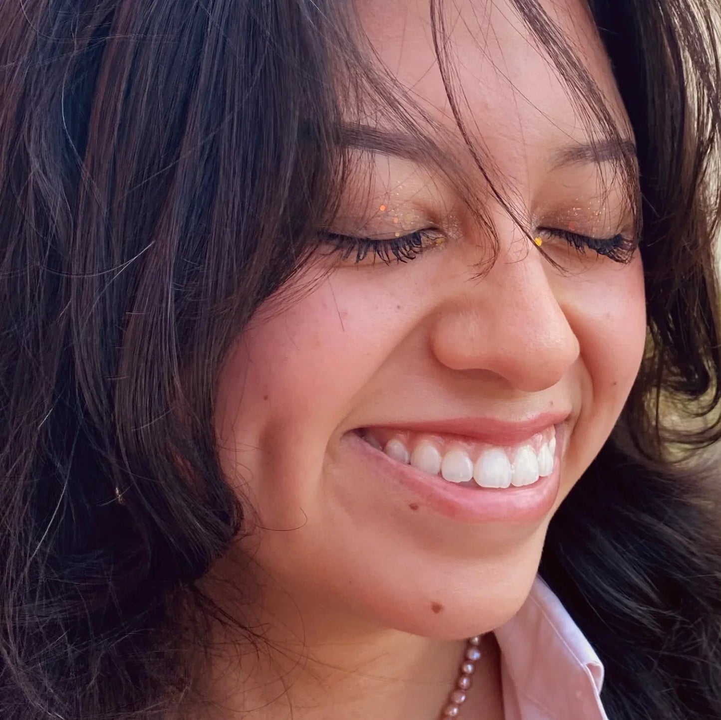 Close-up of a woman smiling with dark hair and a light background