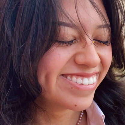 Close-up of a woman smiling with dark hair and a light background