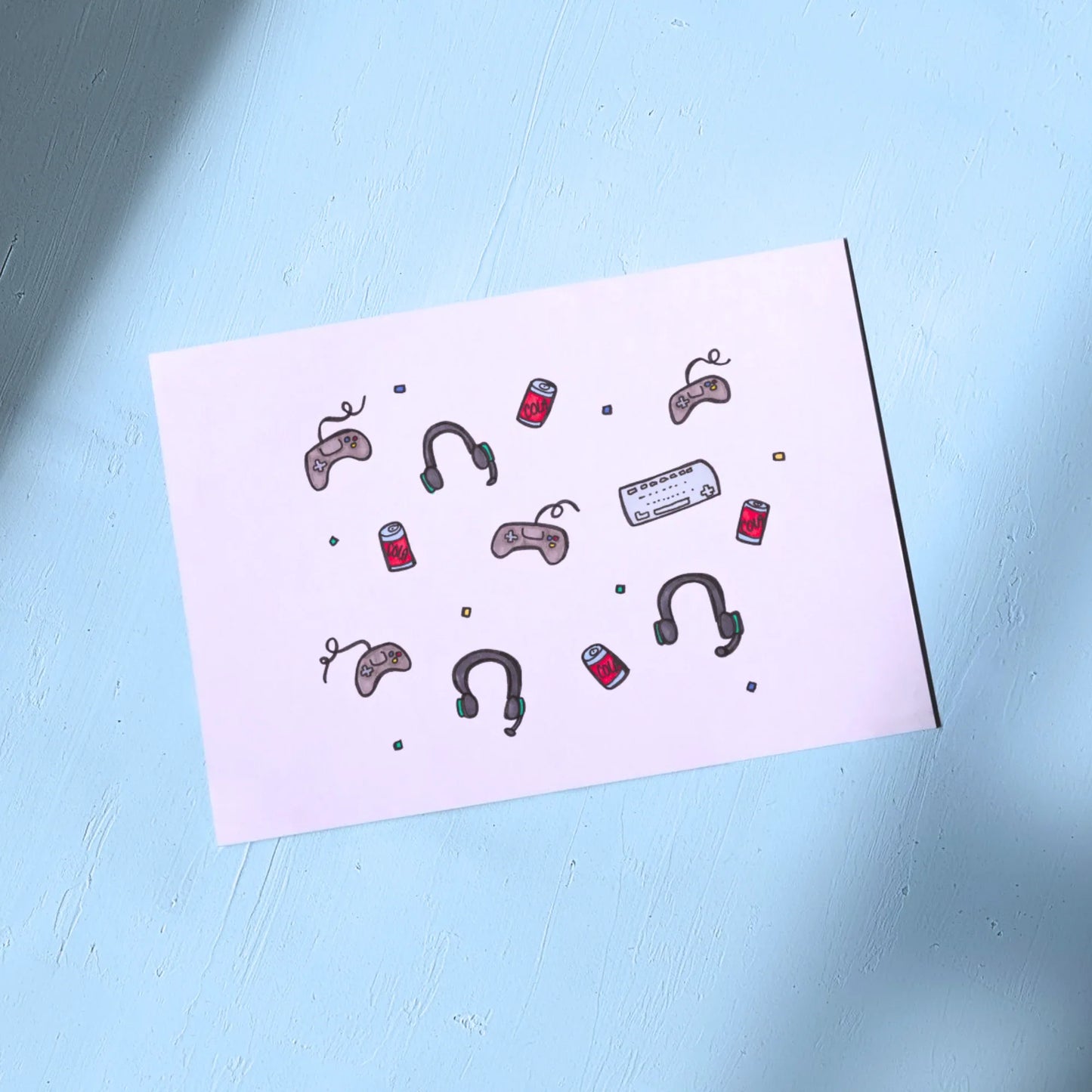 White Greeting Card with illustrations of gaming controllers and soda cans on a light blue background