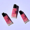 A trio of Lemon Box Beauty Strawberry Lemonade High-Shine Squeeze Lip Glosses—clear pink vegan lip oil tubes containing cute pink strawberry clay slices on a lavender background