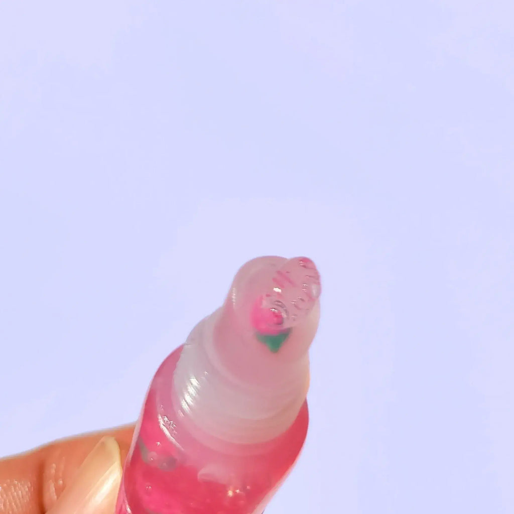 A trio of Lemon Box Beauty Strawberry Lemonade High-Shine Squeeze Lip Glosses—clear pink vegan lip oil tubes containing cute pink strawberry clay slices on a lavender background
