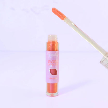 Lemon Box Beauty Grapeseed Vitamin E Lip Gloss in shade Gilded - shimmering copper-gold hydrating lip oil in a clear tube against a lavender background.