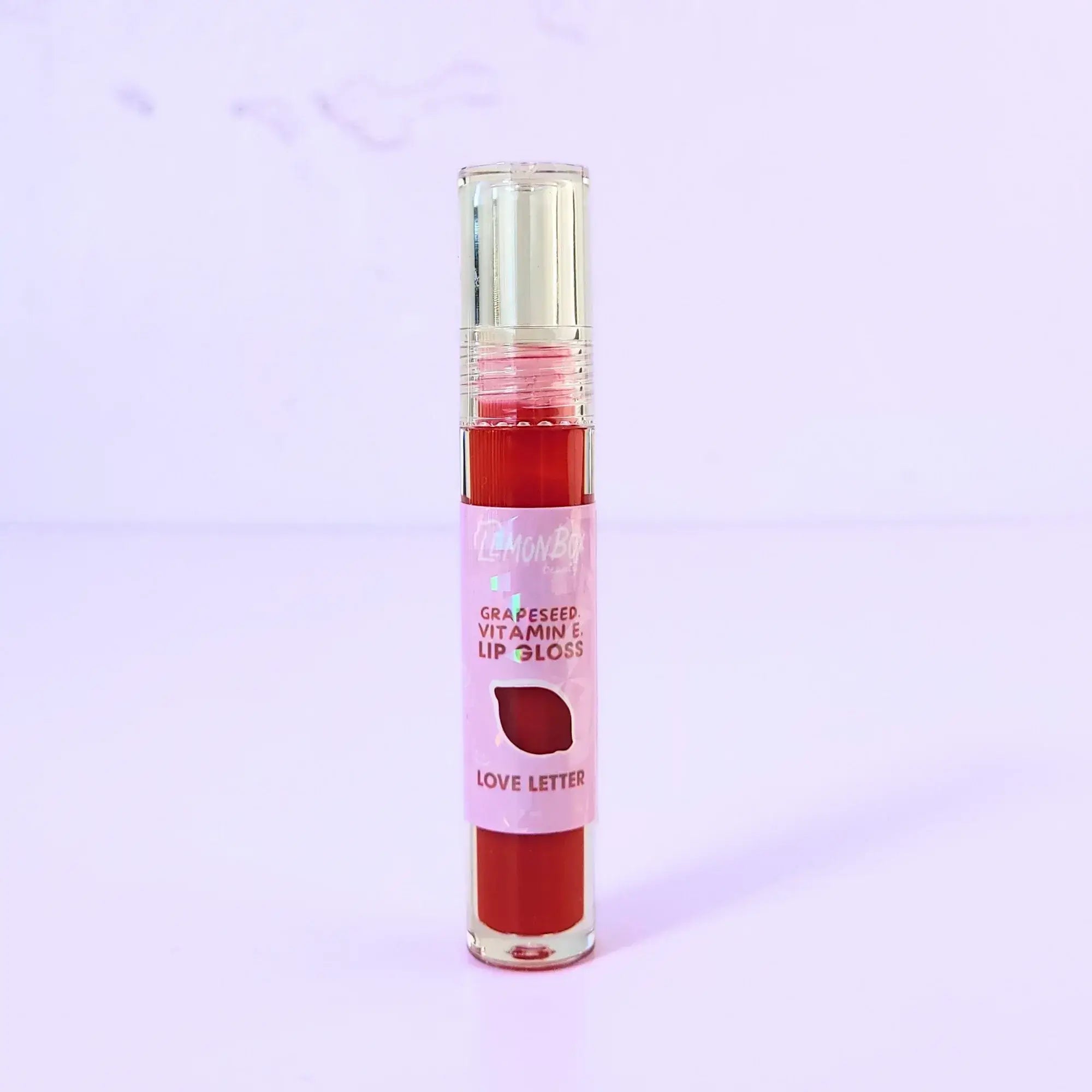 Lemon Box Beauty Grapeseed Vitamin E Lip Gloss in shade Love Letter - vibrant classic red hydrating lip oil in a clear tube against a lavender background.