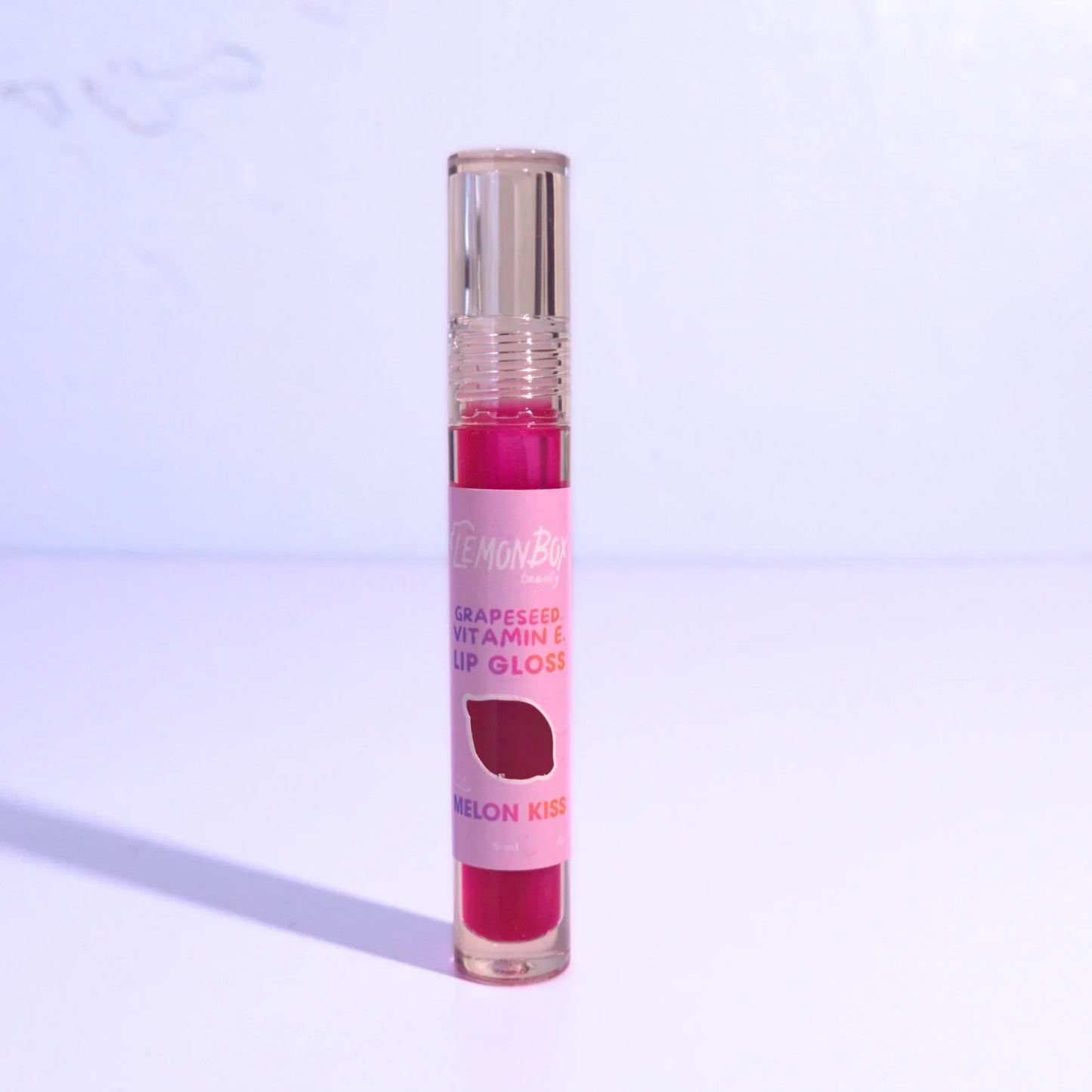 Pink lip gloss with a clear cap on a light purple background