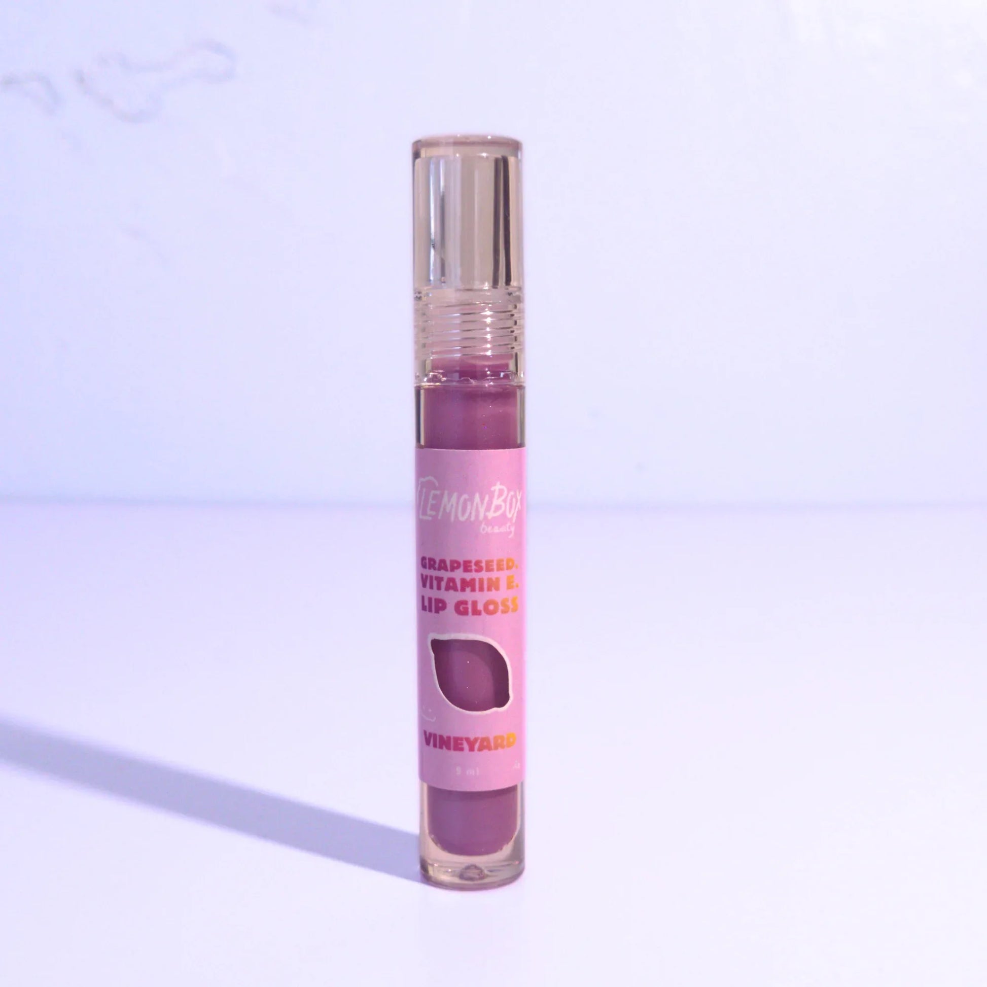 Lip gloss with a purple shade on a light purple background
