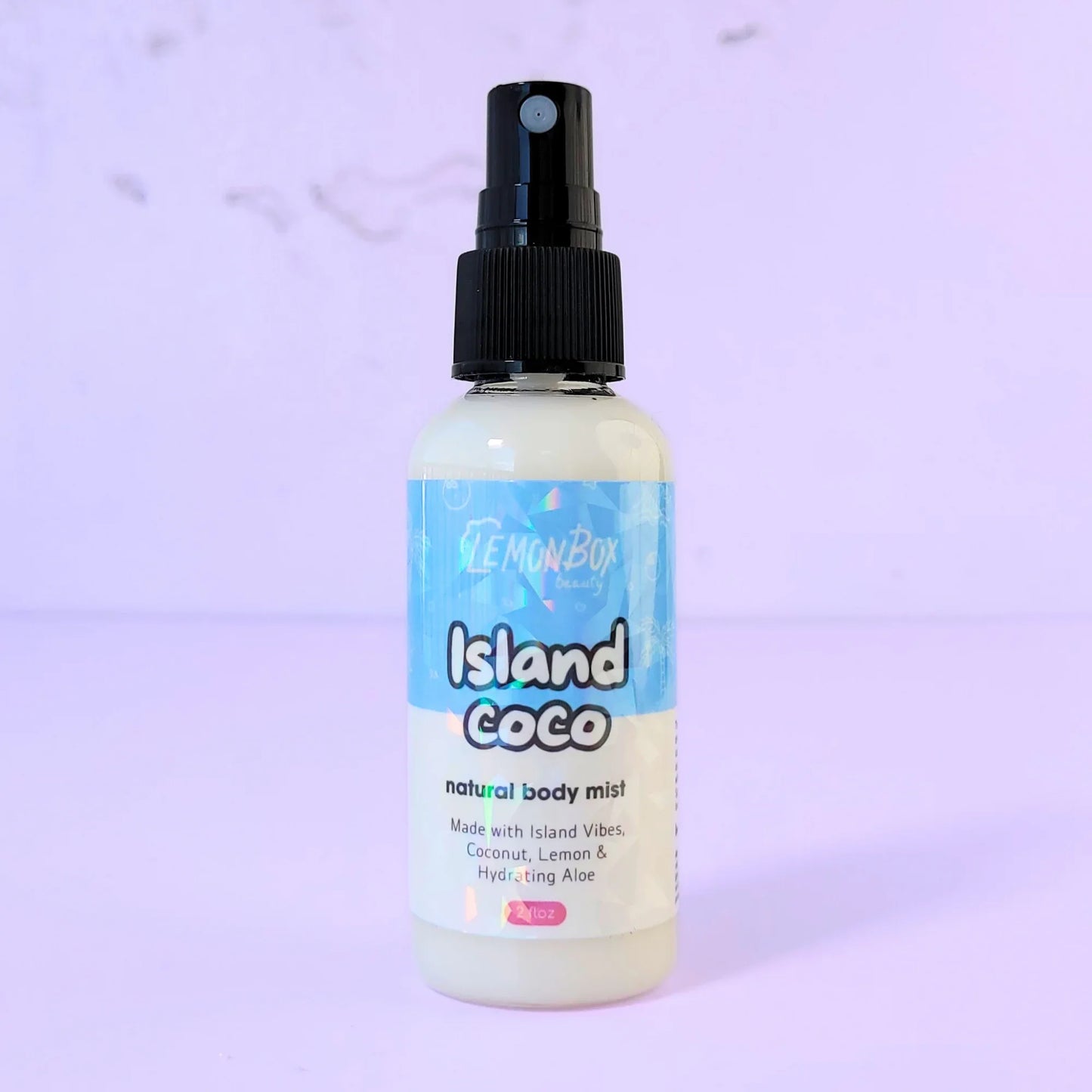 Lemon Box Beauty Island Coco Natural Body Mist - clear spray bottle of tropical coconut and vanilla scented fragrance on a lavender background.