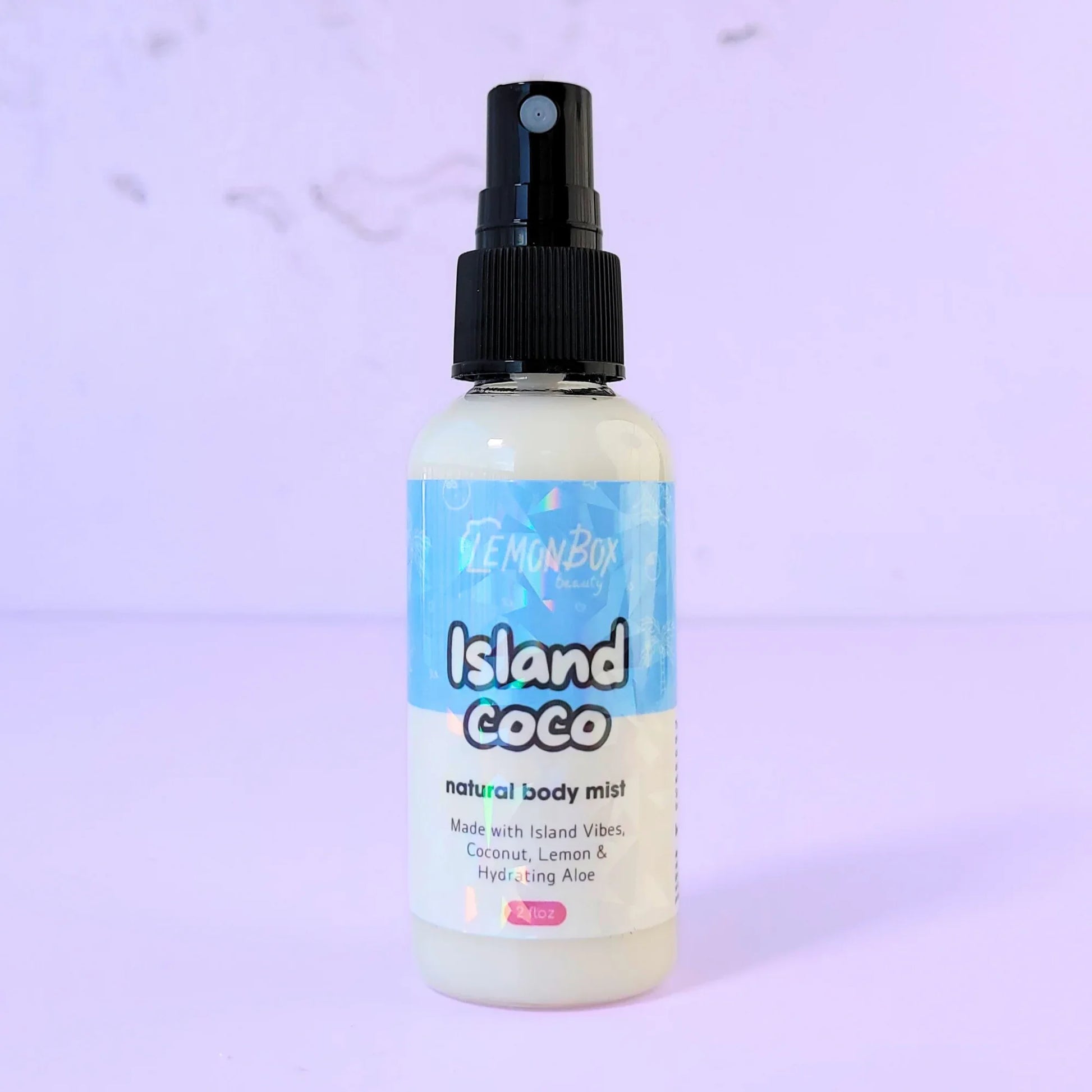 Lemon Box Beauty Island Coco Natural Body Mist - clear spray bottle of tropical coconut and vanilla scented fragrance on a lavender background.