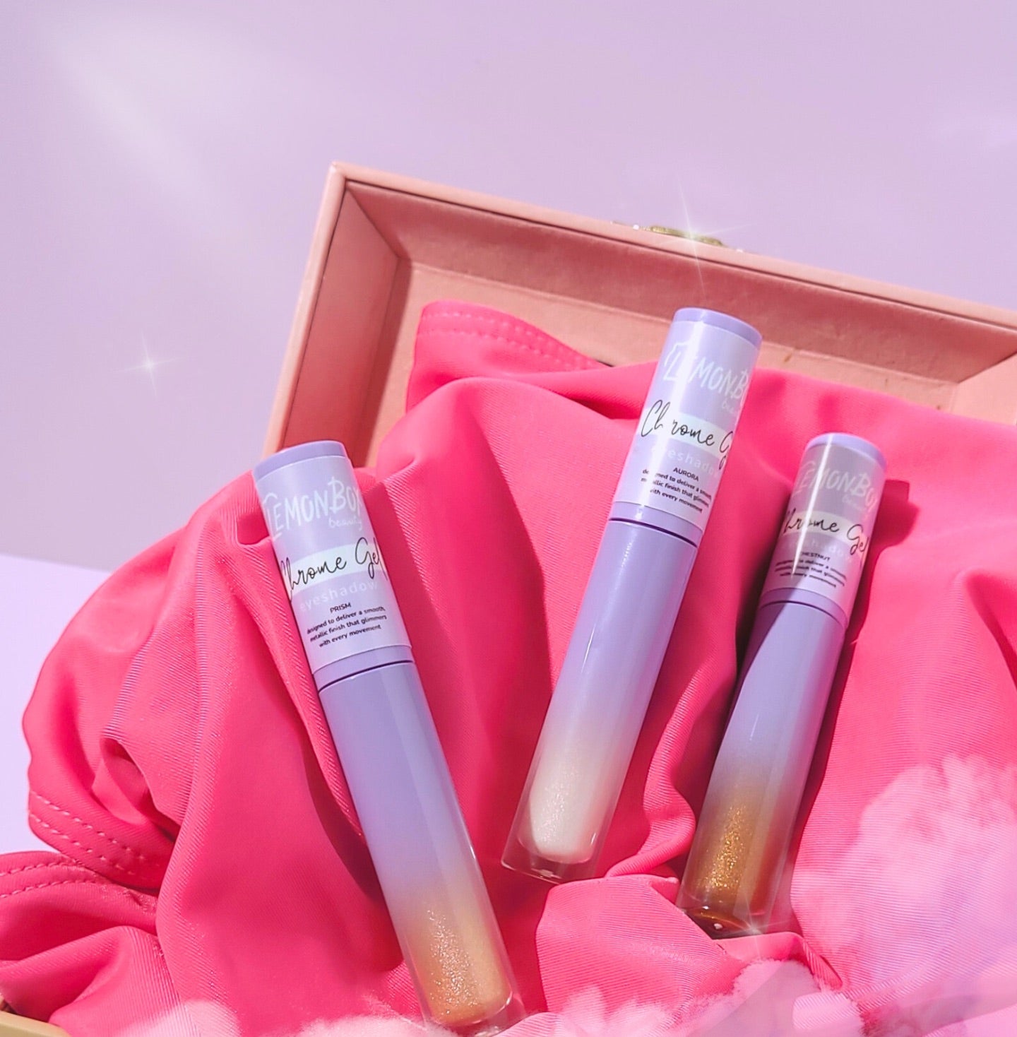 Three gradient lip glosses in a wooden box with pink fabric