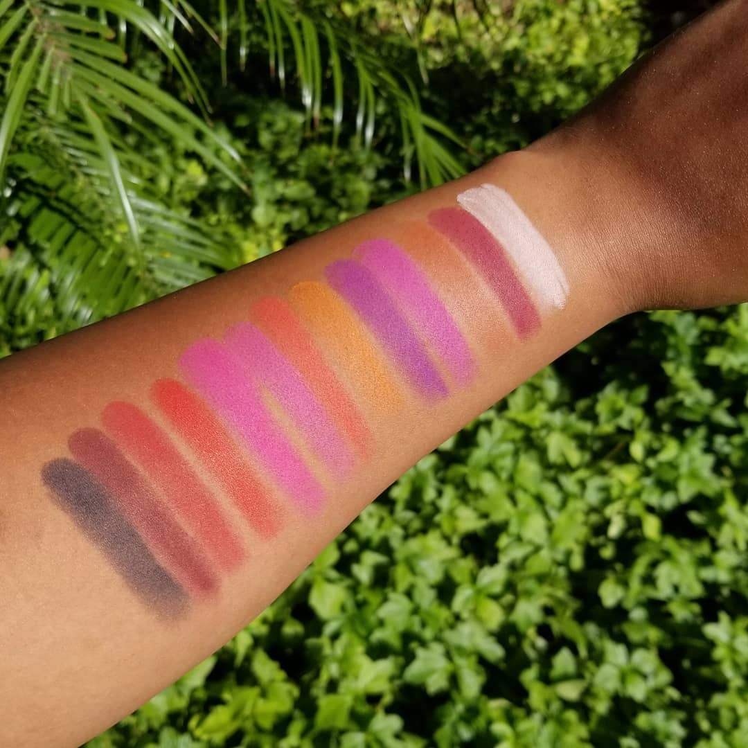 Eyeshadow swatches on a person's arm with a green leafy background