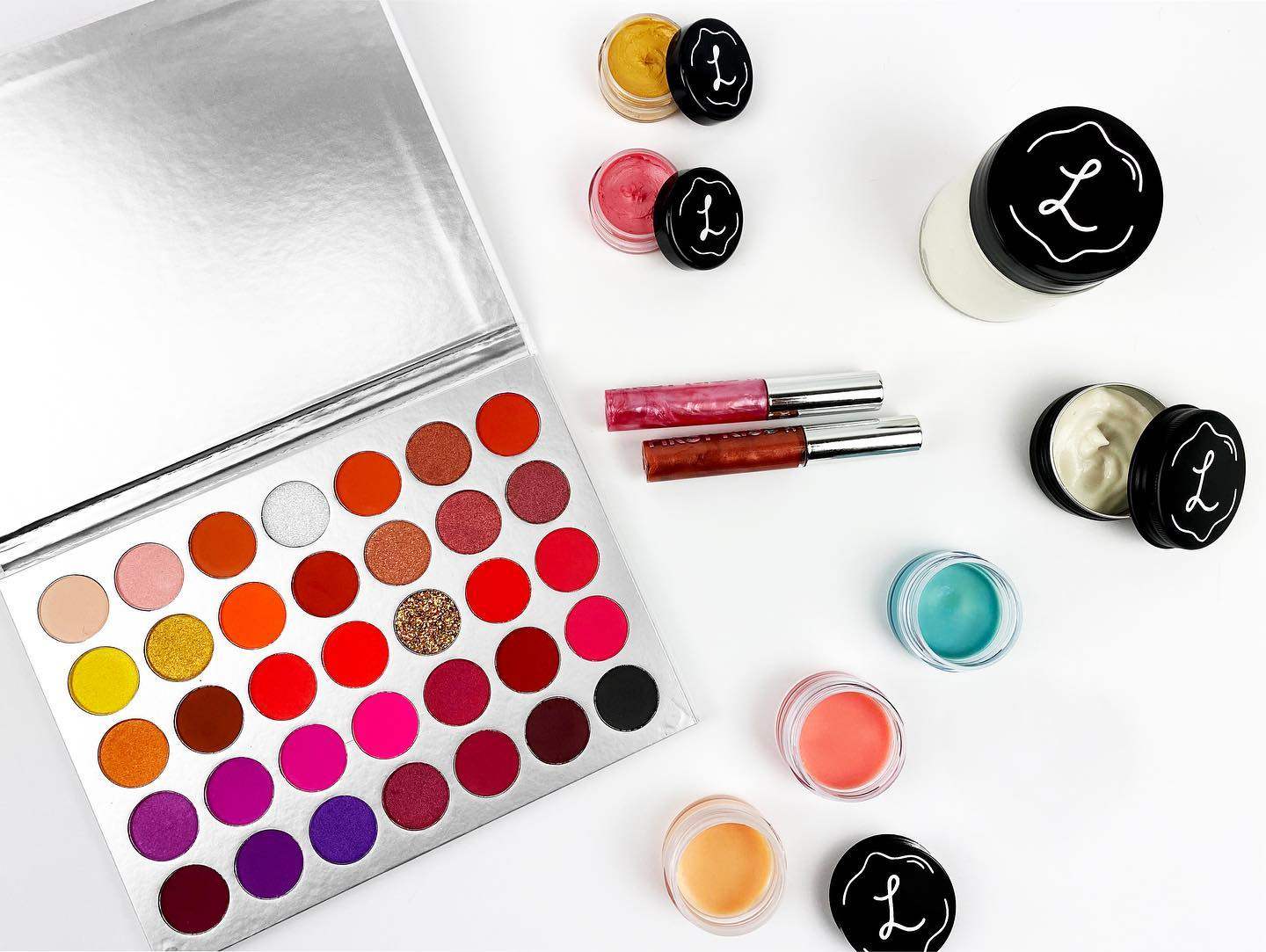Makeup products including a color palette, lip glosses, and lipsticks on a white background. Lemonade stand cosmetics