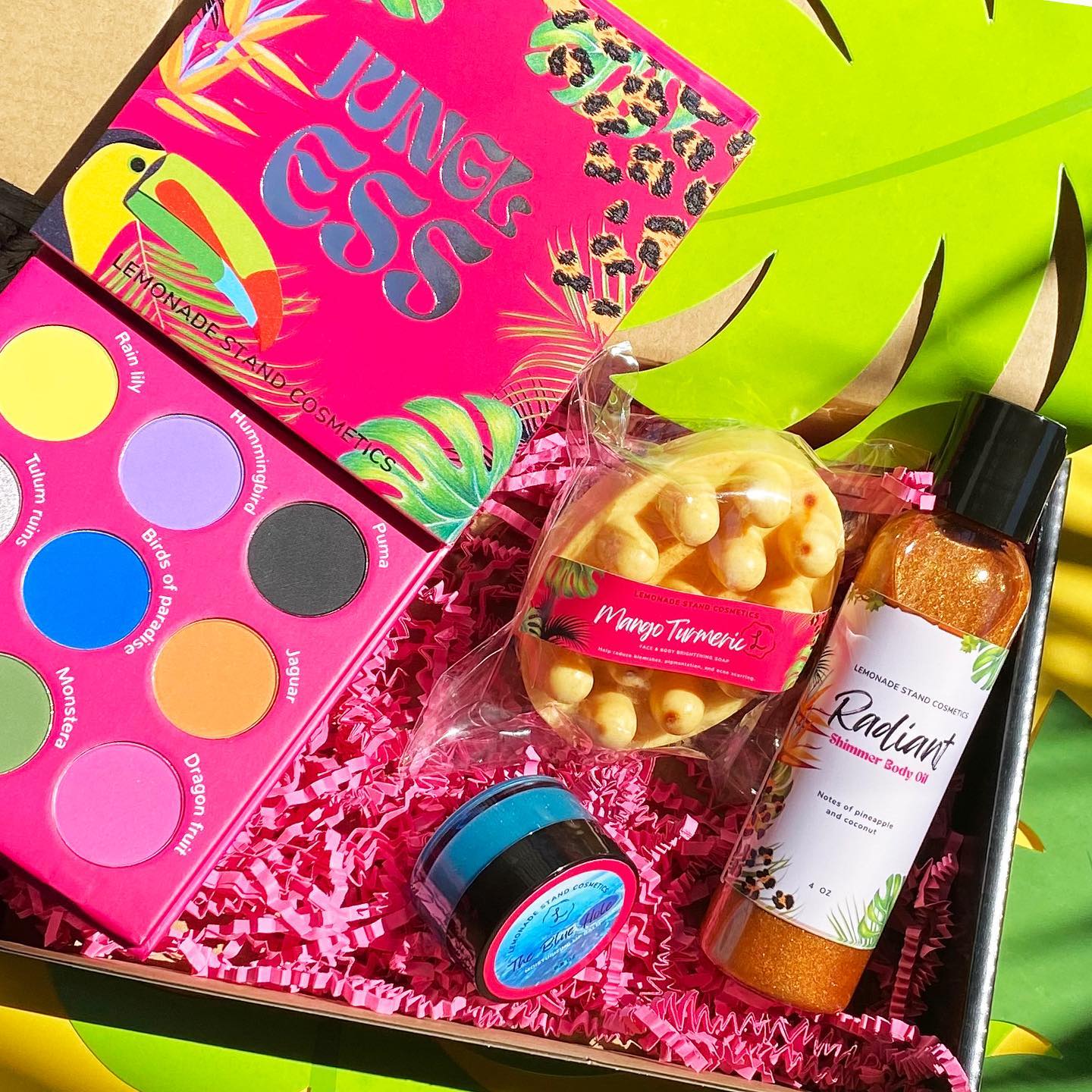 Colorful makeup palette, body scrub, and other items in a decorative box with a tropical theme.