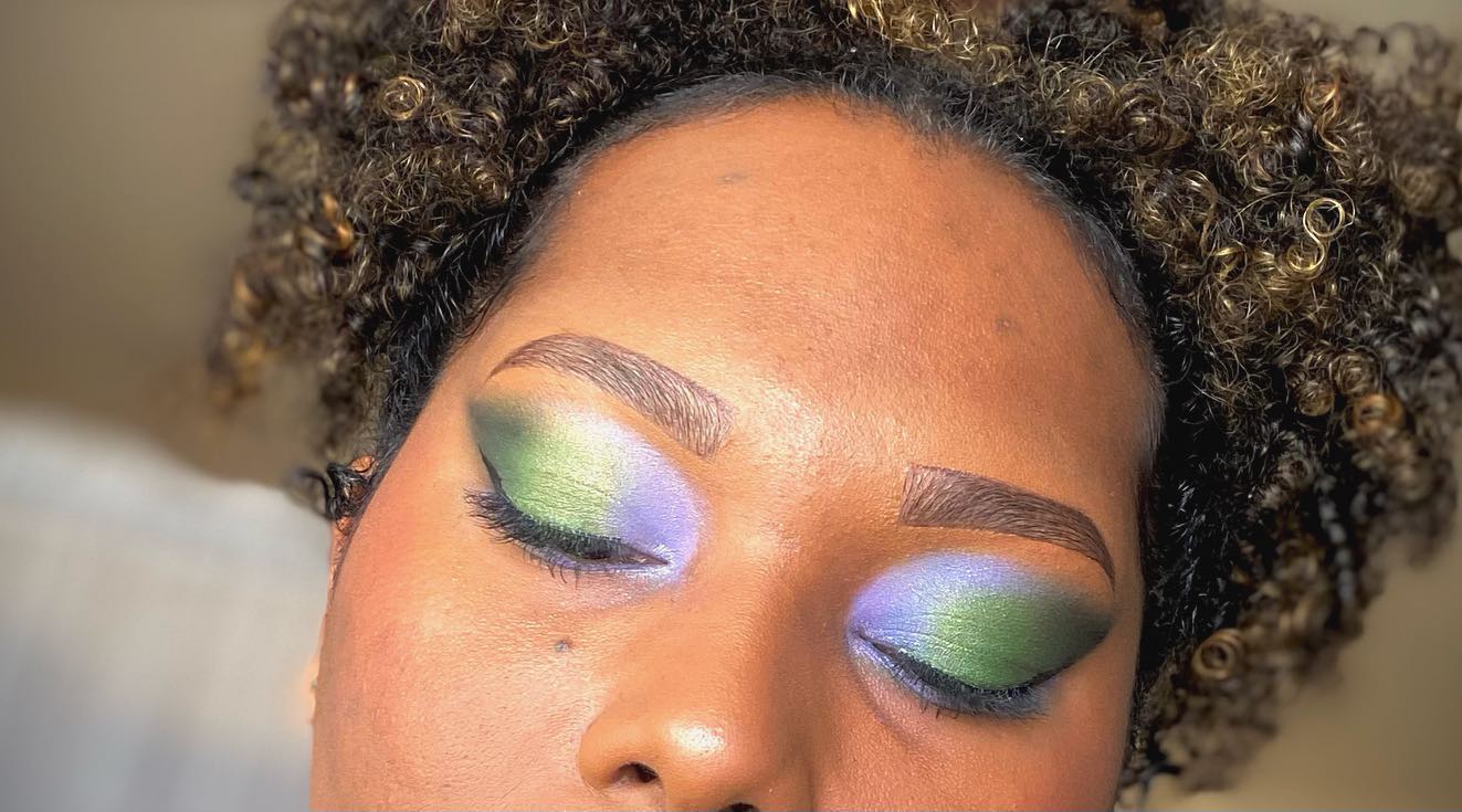 Close-up of a person with colorful eye makeup and an afro hairstyle.