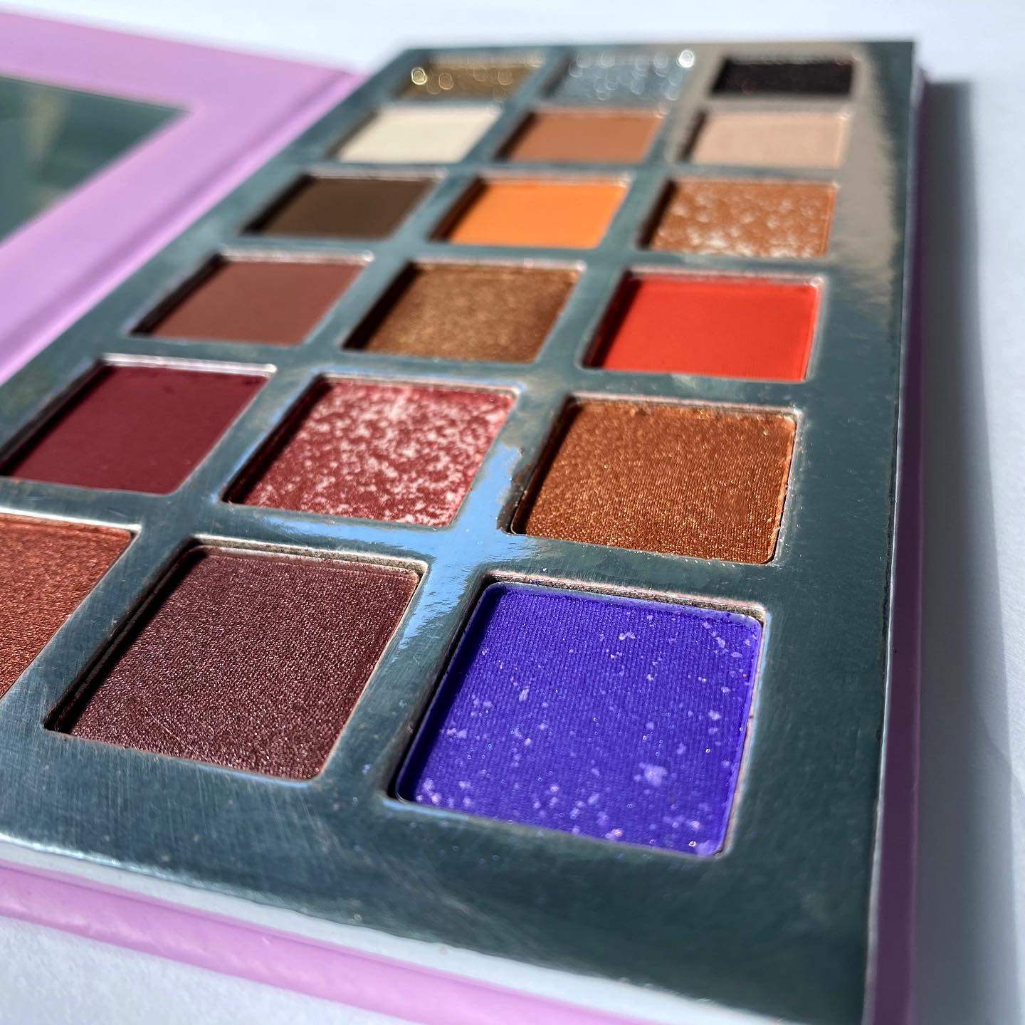 Makeup eyeshadow palette with various colors on a light gray background