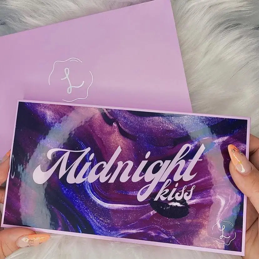 Makeup palette with 'Midnight Kiss' text held by a hand, against a purple background.