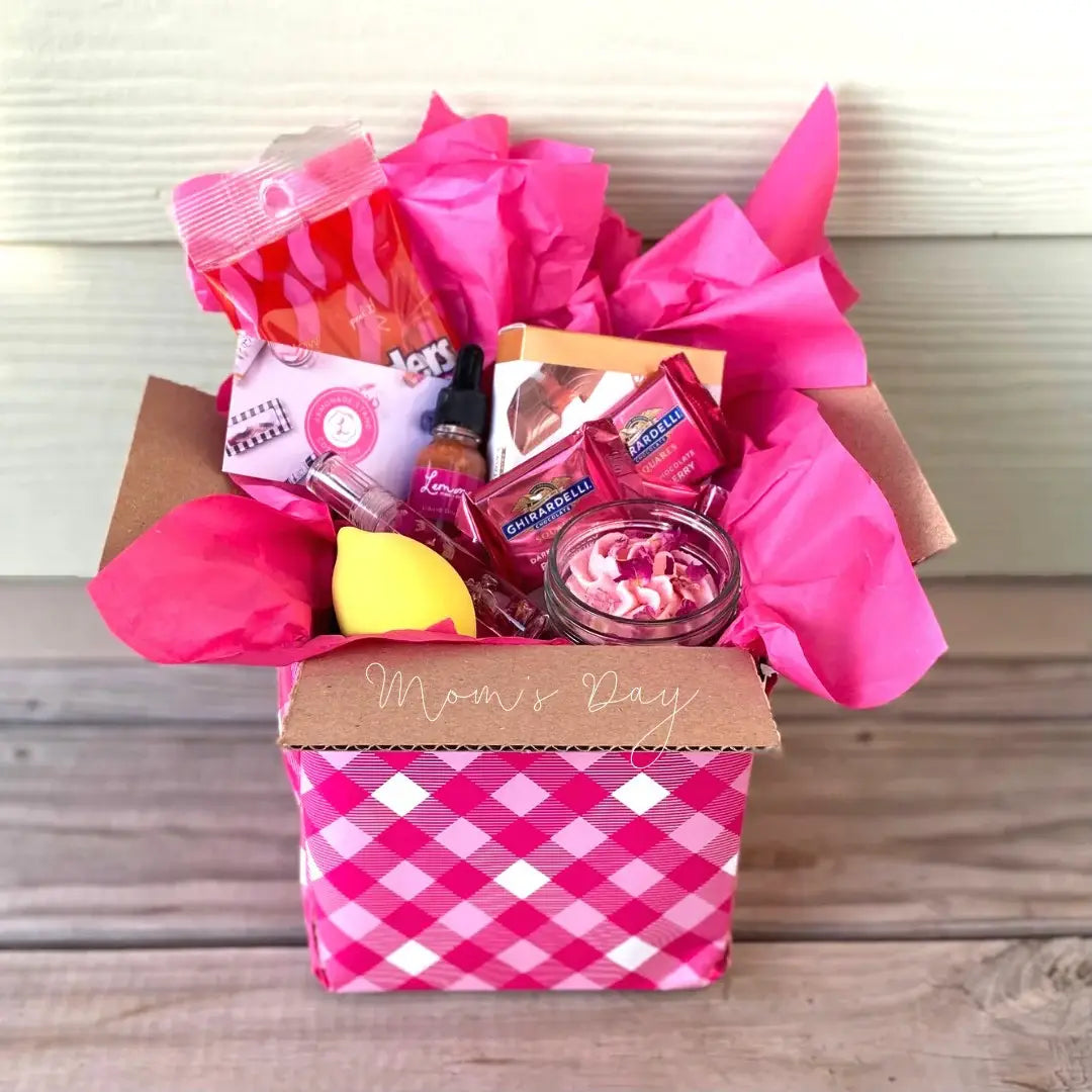 Gift basket with pink and white checkered box labeled 'Mom's Day' on a wooden surface.