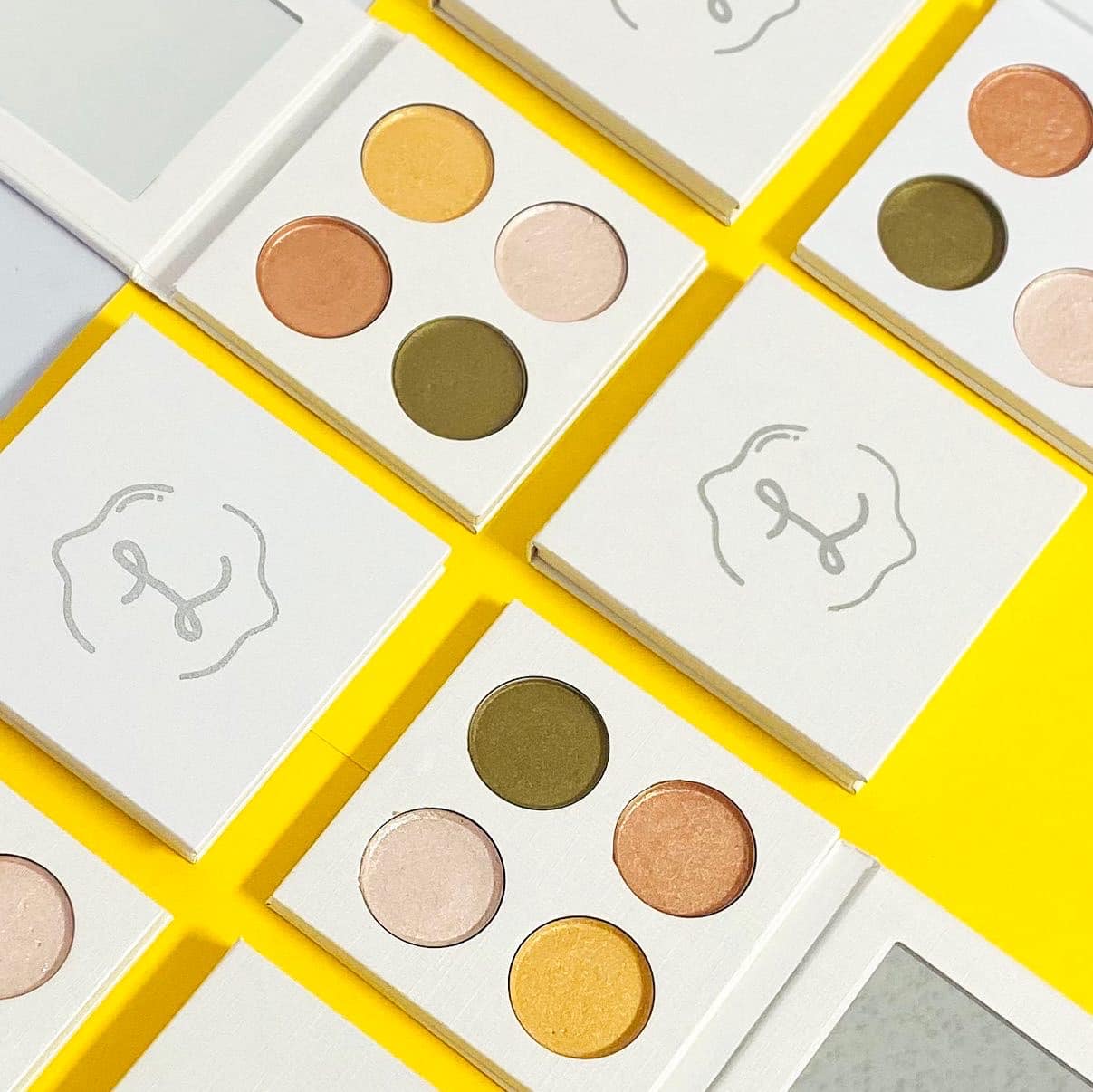 Makeup eyeshadow palettes with a brand logo on yellow and white backgrounds
