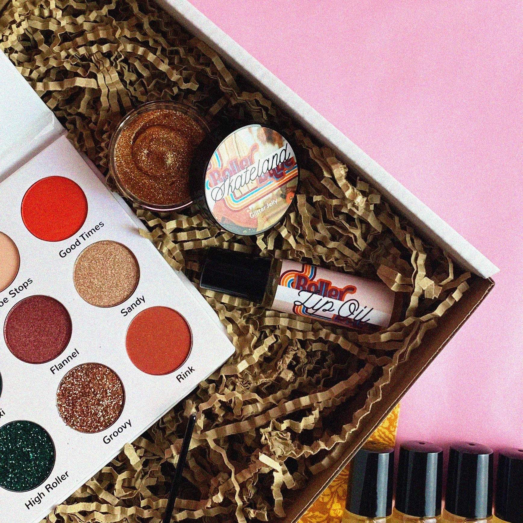 Makeup set with a palette, lip balm, and other items in a box on a pink background