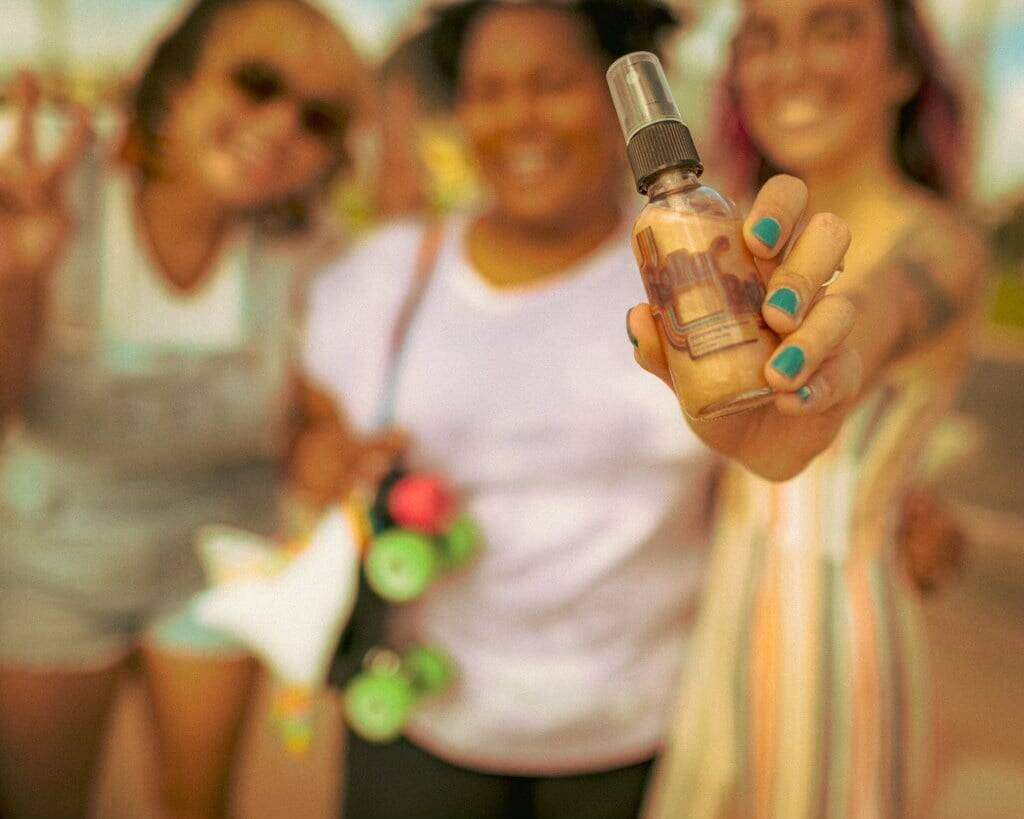 Person holding a small bottle with a colorful background of people.
