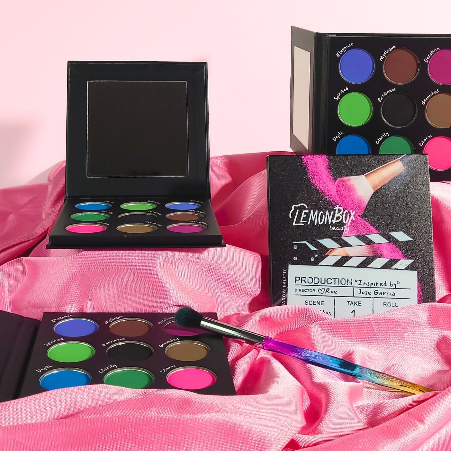 Makeup palettes with colorful shades on a pink fabric background