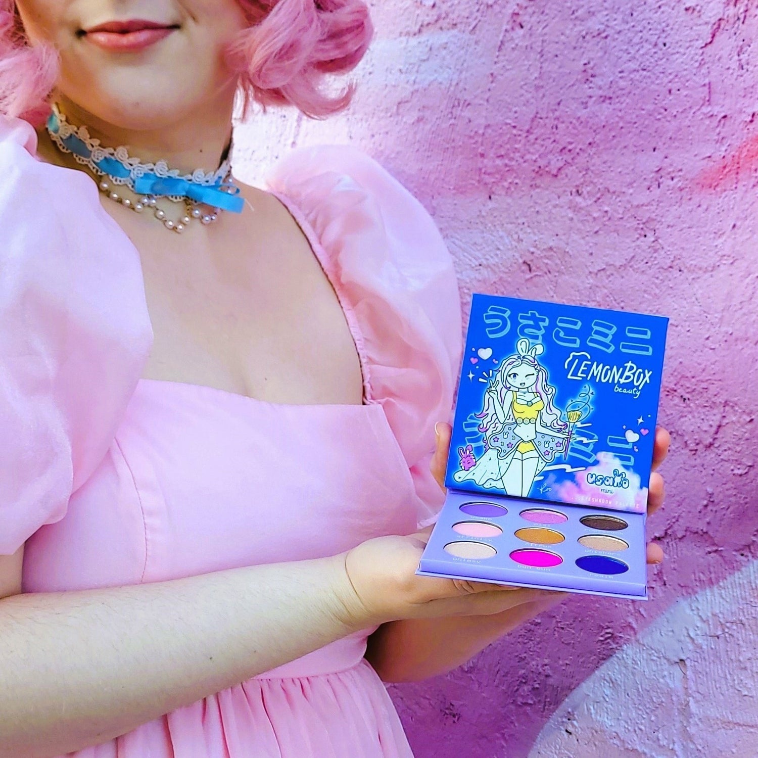 Person holding a colorful makeup palette with a pink and blue background Usako mini