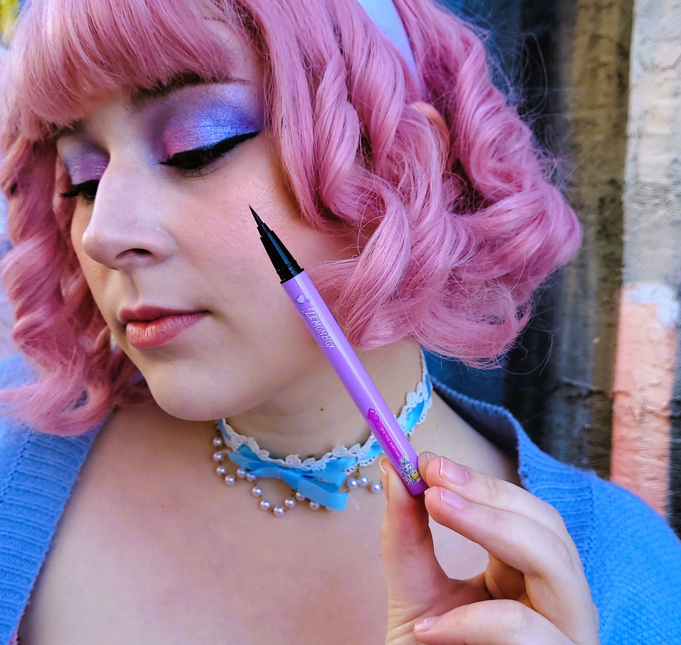 Person with pink hair holding a purple marker outdoors