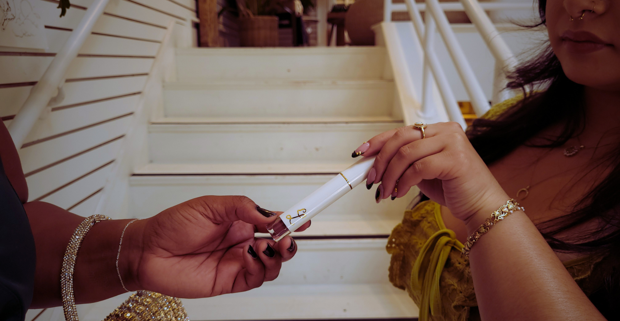 Two hands exchanging a small object on a staircase.