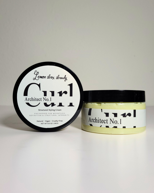 A jar of Architect No. 1 Structured Styling Cream next to its lid, which displays 'Lemon Thru Cream' in script and bold text.