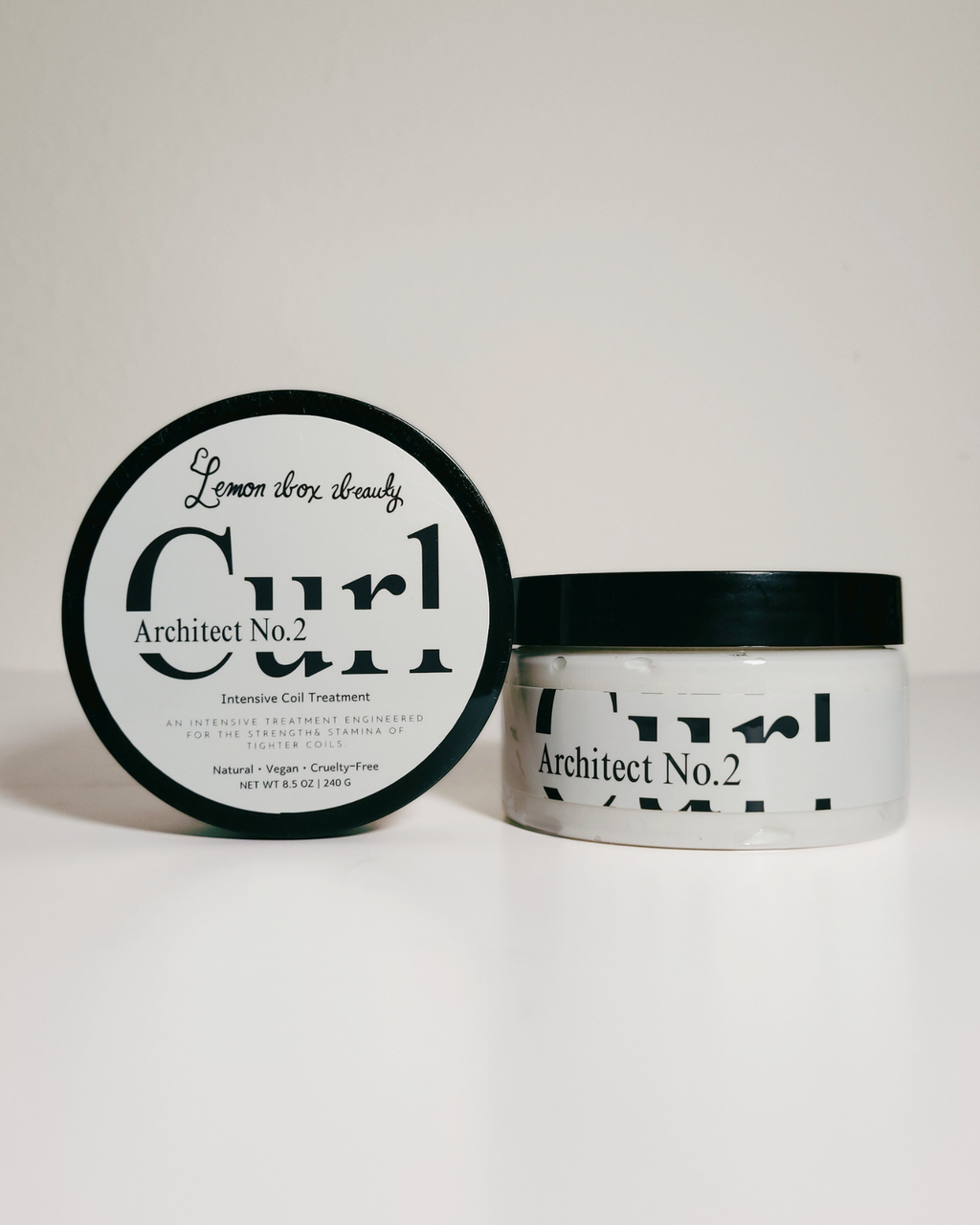 A jar of Architect No. 2 curl cream with its lid placed beside it on a clean white background.