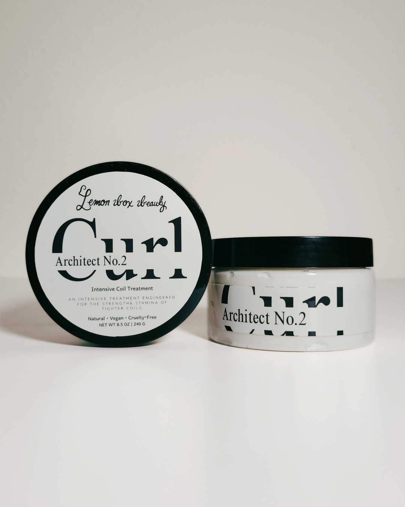 A jar of Architect No. 2 curl cream with its lid placed beside it on a clean white background.