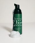A dark green pump bottle of Kline Lemon Breeze Facial Cleanser with white text, shown on a white background with a dollop of white foam in front.