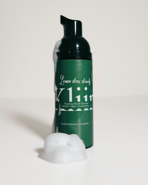 A dark green pump bottle of Kline Lemon Breeze Facial Cleanser with white text, shown on a white background with a dollop of white foam in front.