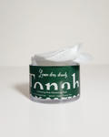 A clear plastic jar of Tonah Lemon Drop Exfoliating Pads with a dark green label and white text, shown with a white pad pulled from the open top against a plain light background.