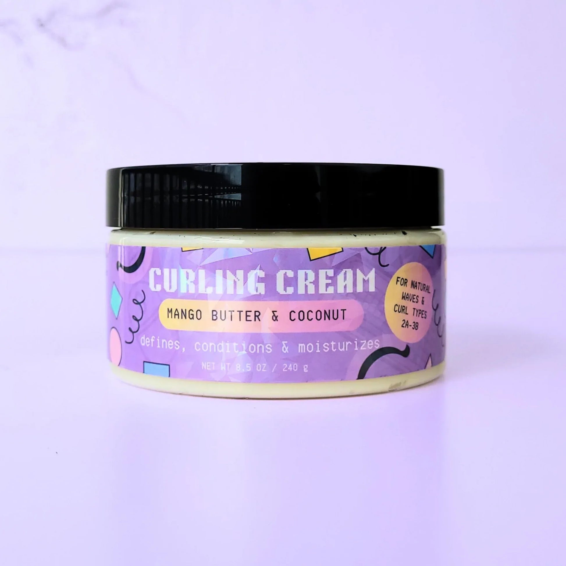 An 8.5 oz jar of LemonBox Beauty Curling Cream featuring Mango Butter and Coconut, with a purple geometric label and a black lid, set against a soft lavender background.