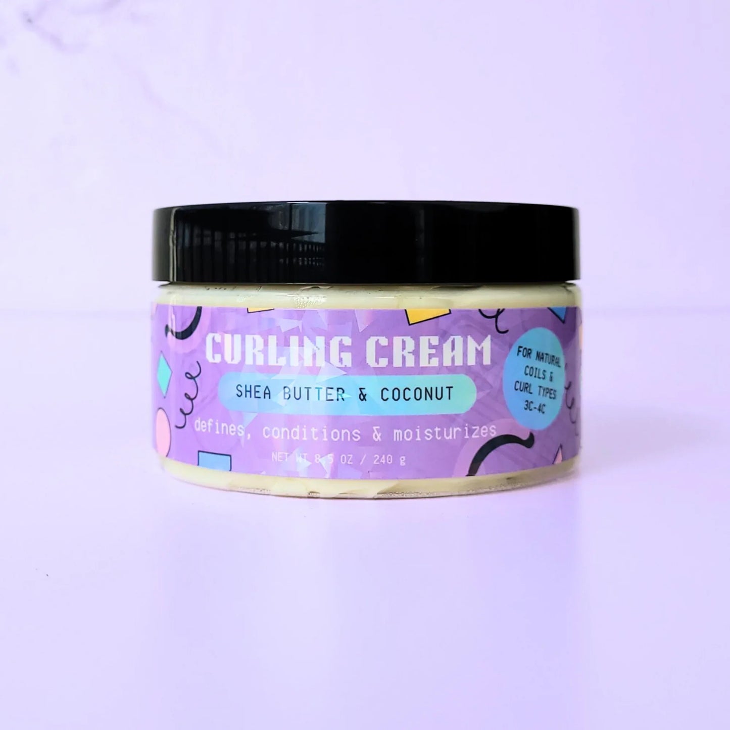An 8.5 oz jar of LemonBox Beauty Curling Cream featuring Shea Butter and Coconut, with a blue and purple geometric label and a black lid, set against a soft lavender background.
