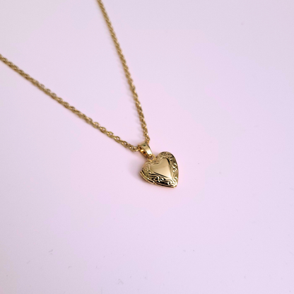 Gold heart-shaped pendant necklace on a light pink background