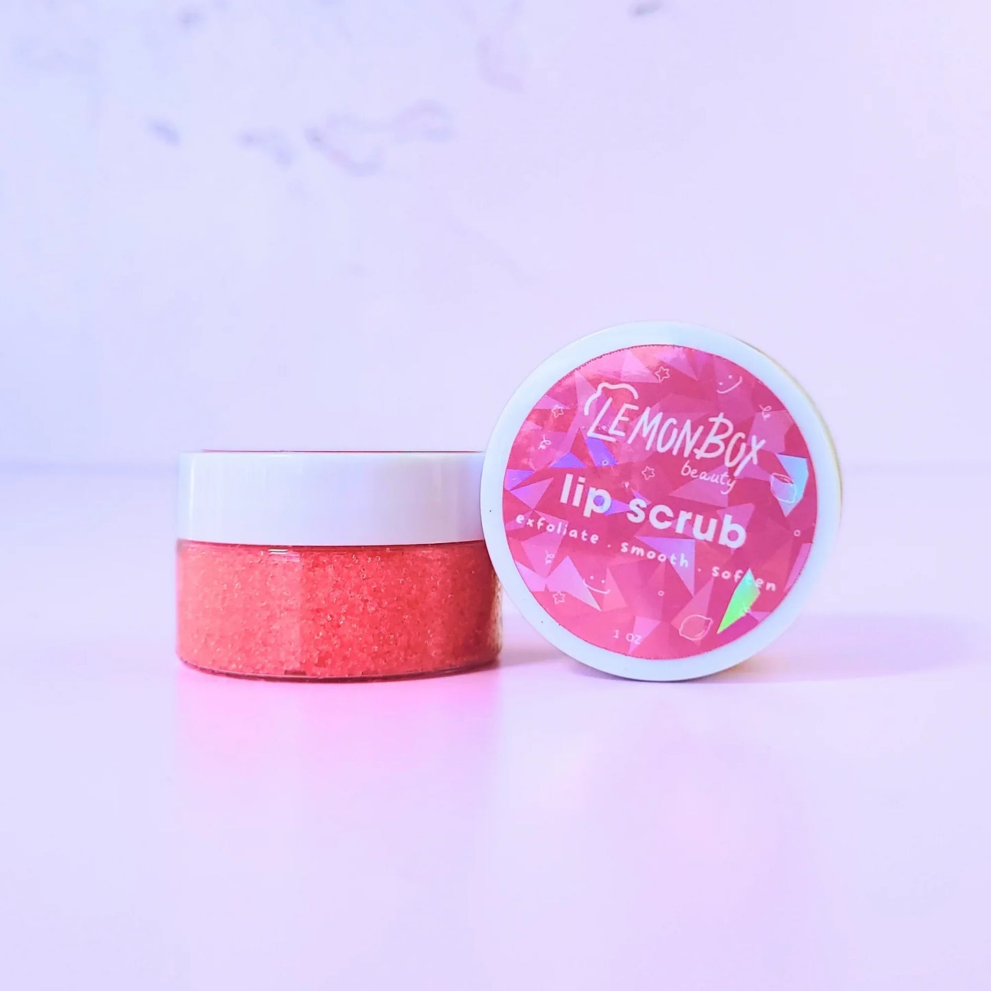 Lemon Box Beauty Strawberry Coconut Lip Scrub - 1oz jar of pink sugar scrub to exfoliate, smooth, and soften lips on a lavender background.