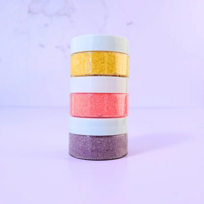 Lemon Box Beauty collection of three stacked lip scrubs including Lemon Vanilla Bean, Strawberry Coconut, and Vine Picked Blueberry - yellow, pink, and purple exfoliating sugar scrubs.