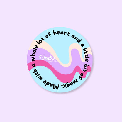 Round sticker with colorful design and text on a light purple background