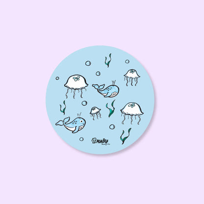 Round blue sticker with ocean-themed illustrations on a light purple background