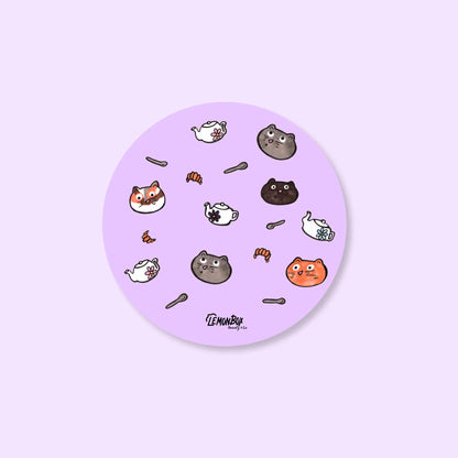 Round purple sticker with cartoon cat illustrations on a light purple background